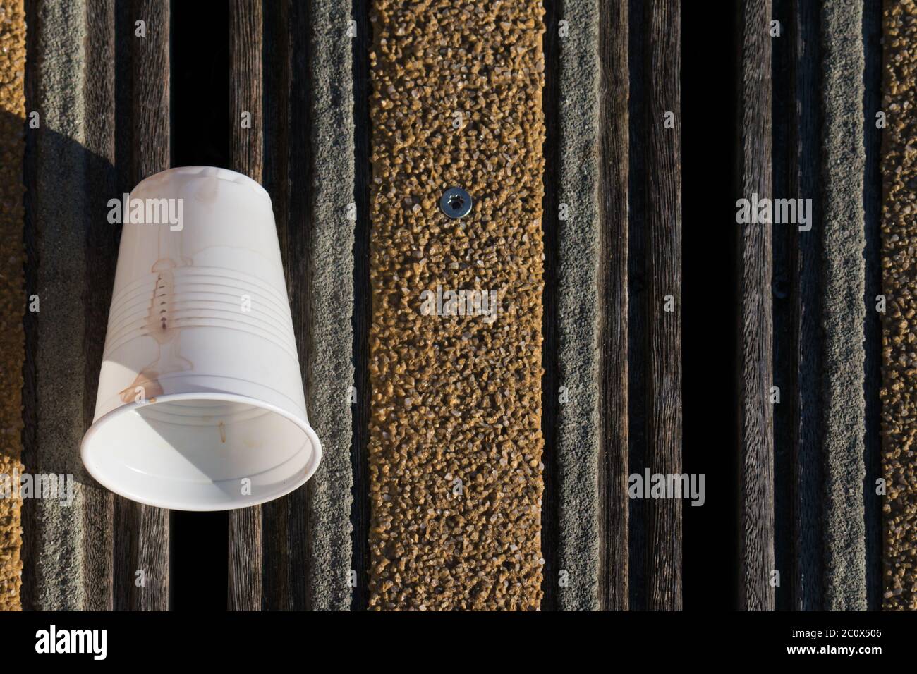 Tasse en plastique blanc qui est parsemante d'un pont en bois Banque D'Images