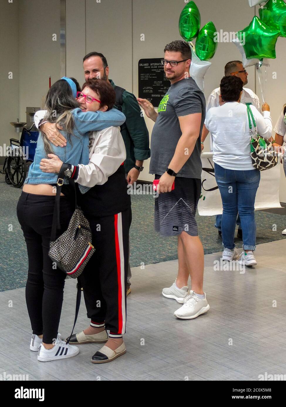 Un passager arrivant est accueilli à l'aéroport international d'Orlando en Floride. Notez les ballons de fête. Banque D'Images