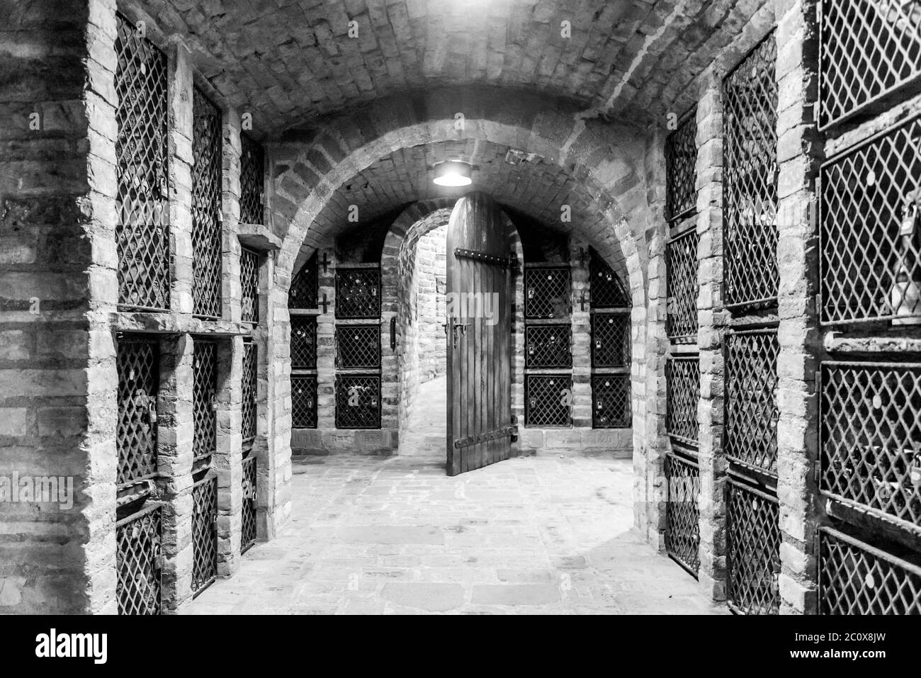 Ancienne cave à vin avec boîtes de stockage et portes en bois d'époque ouvertes. Image en noir et blanc. Banque D'Images