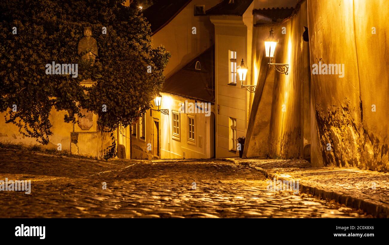 Petite rue pavée dans la vieille ville médiévale avec maisons illuminées par des lampes de rue d'époque, Novy svet, Prague, République tchèque. Prise de vue de nuit. Banque D'Images