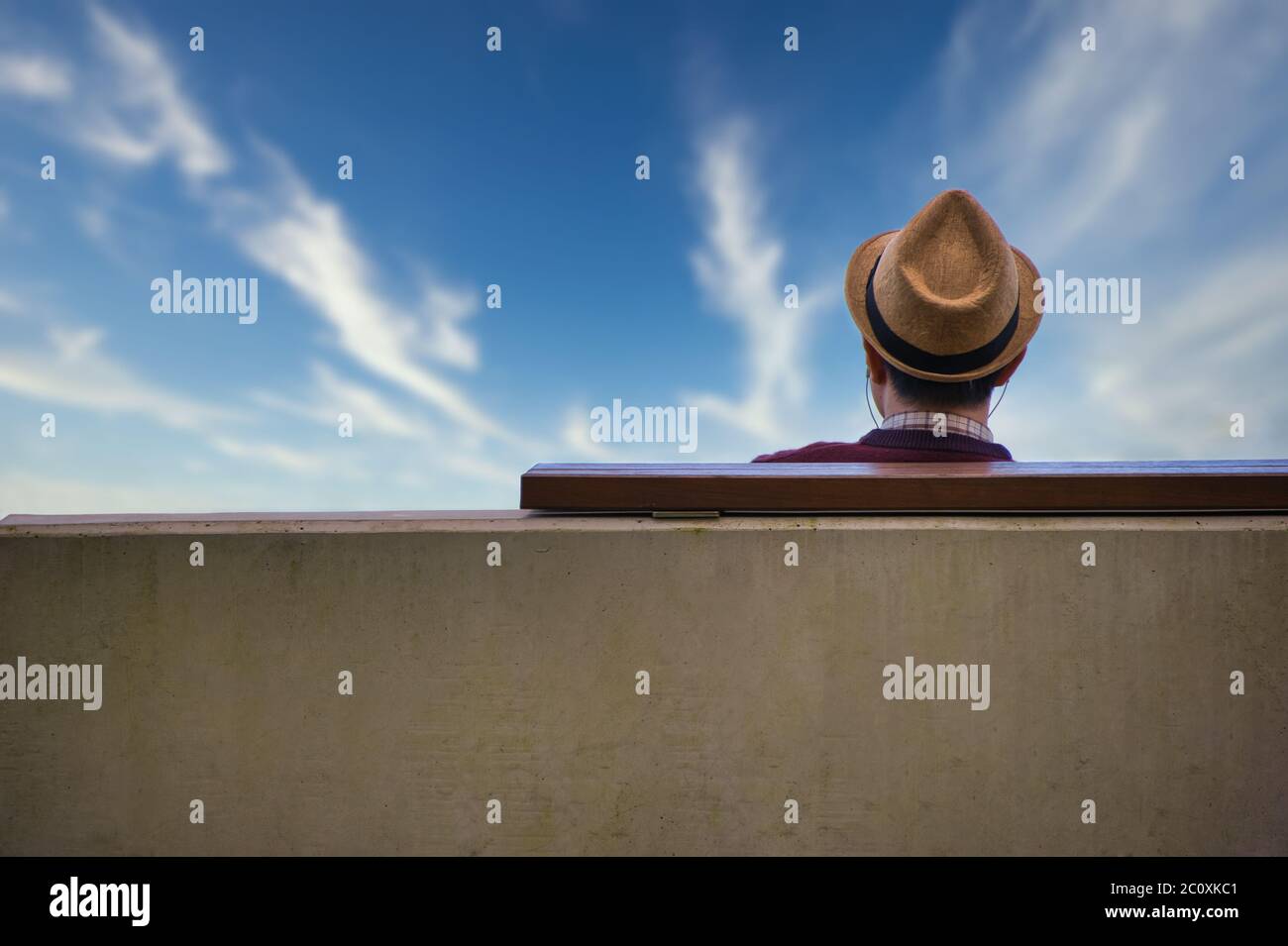 Tourist with a fedora se tient sur un banc de parc en bord de mer, donnant sur l'océan Pacifique bleu sur l'Esplanade à Cairns, Queensland, Australie. Banque D'Images