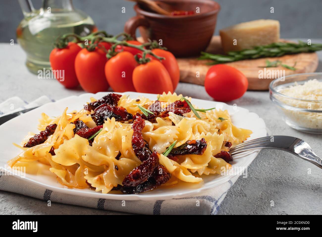 Pâtes avec tomates séchées et parmesan dans une assiette blanche sur la table. Cuisine italienne, ingrédients et plat fini. Banque D'Images