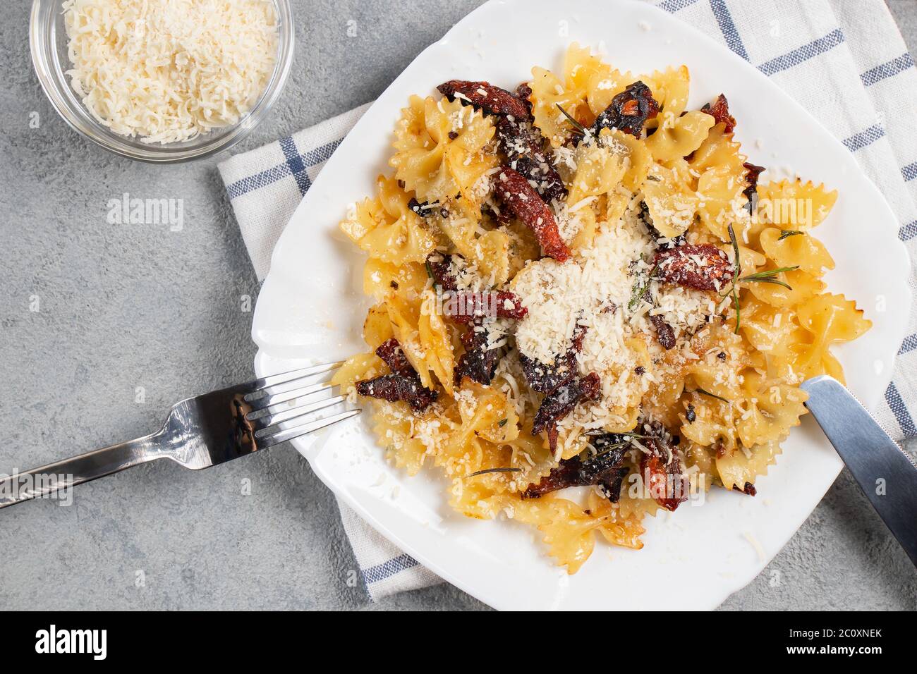 Pâtes avec tomates séchées et parmesan dans une assiette blanche sur la table. Plats italiens, vue de dessus, plat Banque D'Images