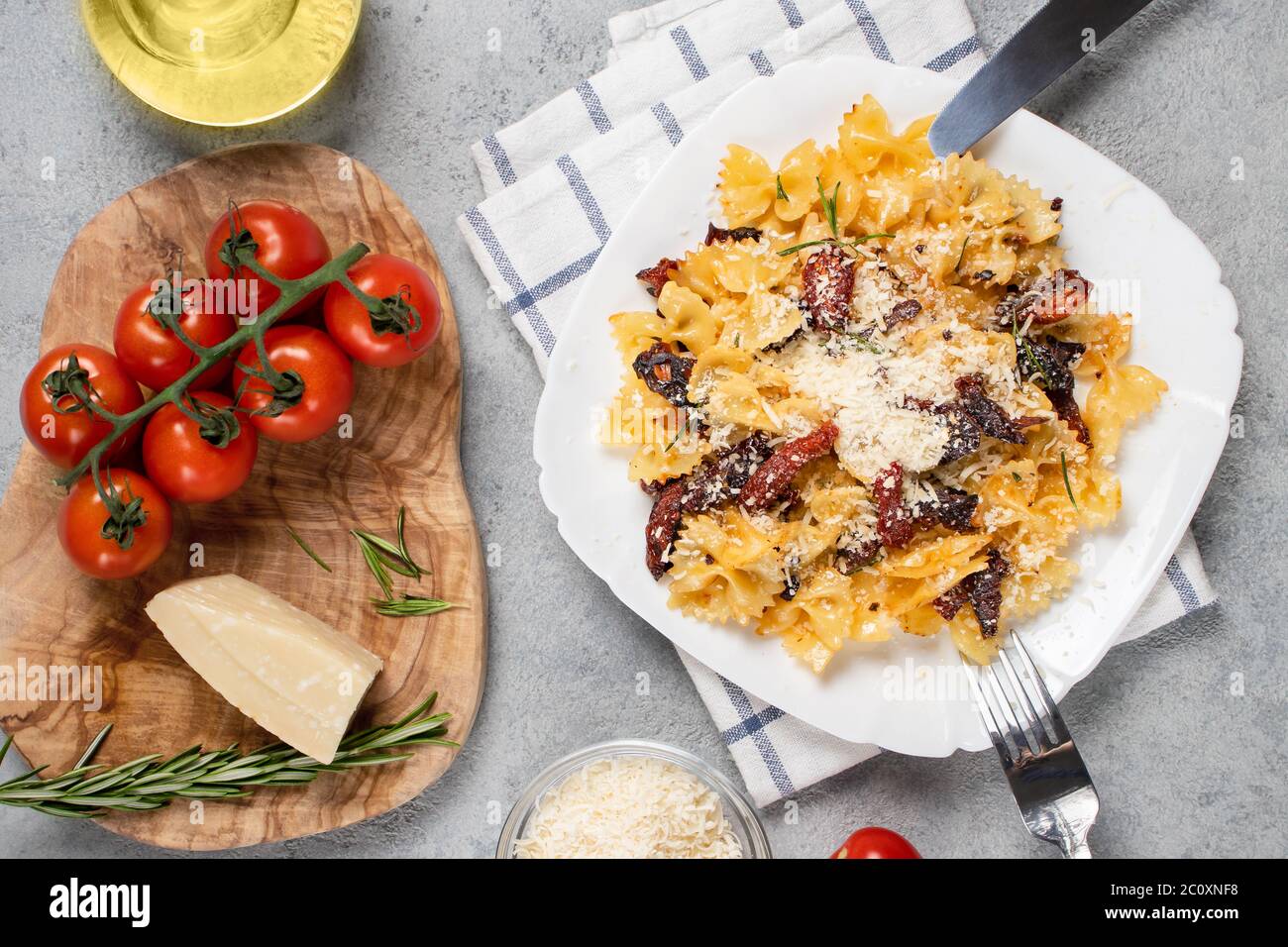 Pâtes avec tomates séchées et parmesan dans une assiette blanche sur la table. Cuisine italienne, ingrédients et plat, vue sur le dessus, plat. Banque D'Images