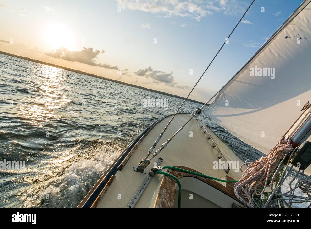 Bateau à voile naviguant rapidement dans le coucher du soleil sur la mer bâclée avec horizon incliné Banque D'Images