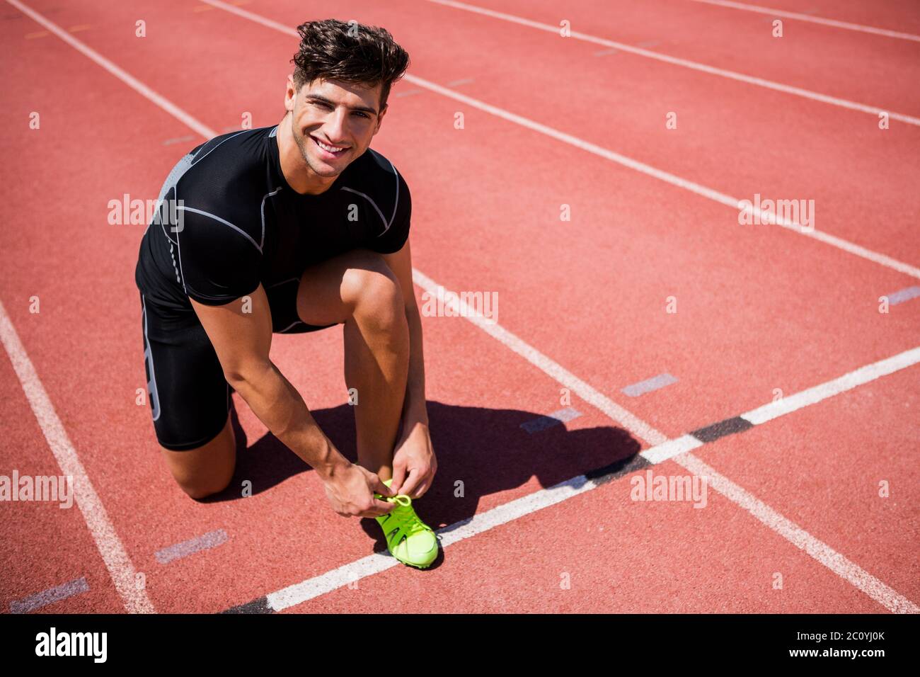 Portrait de l'athlète masculin de lier ses lacets sur une piste de course Banque D'Images