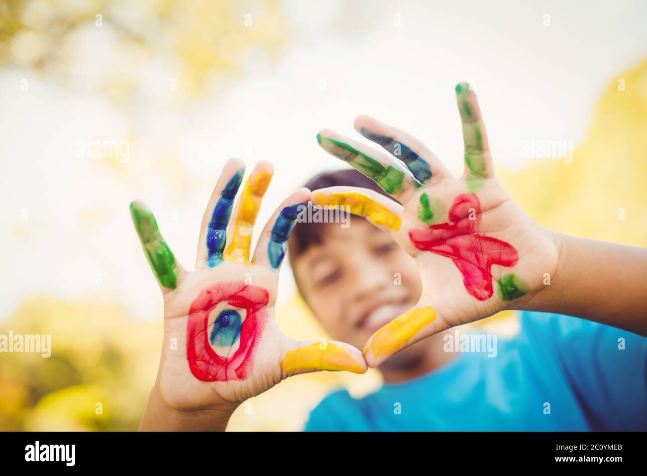 Garçon faisant un cercle pour l'appareil photo avec ses mains peint Banque D'Images