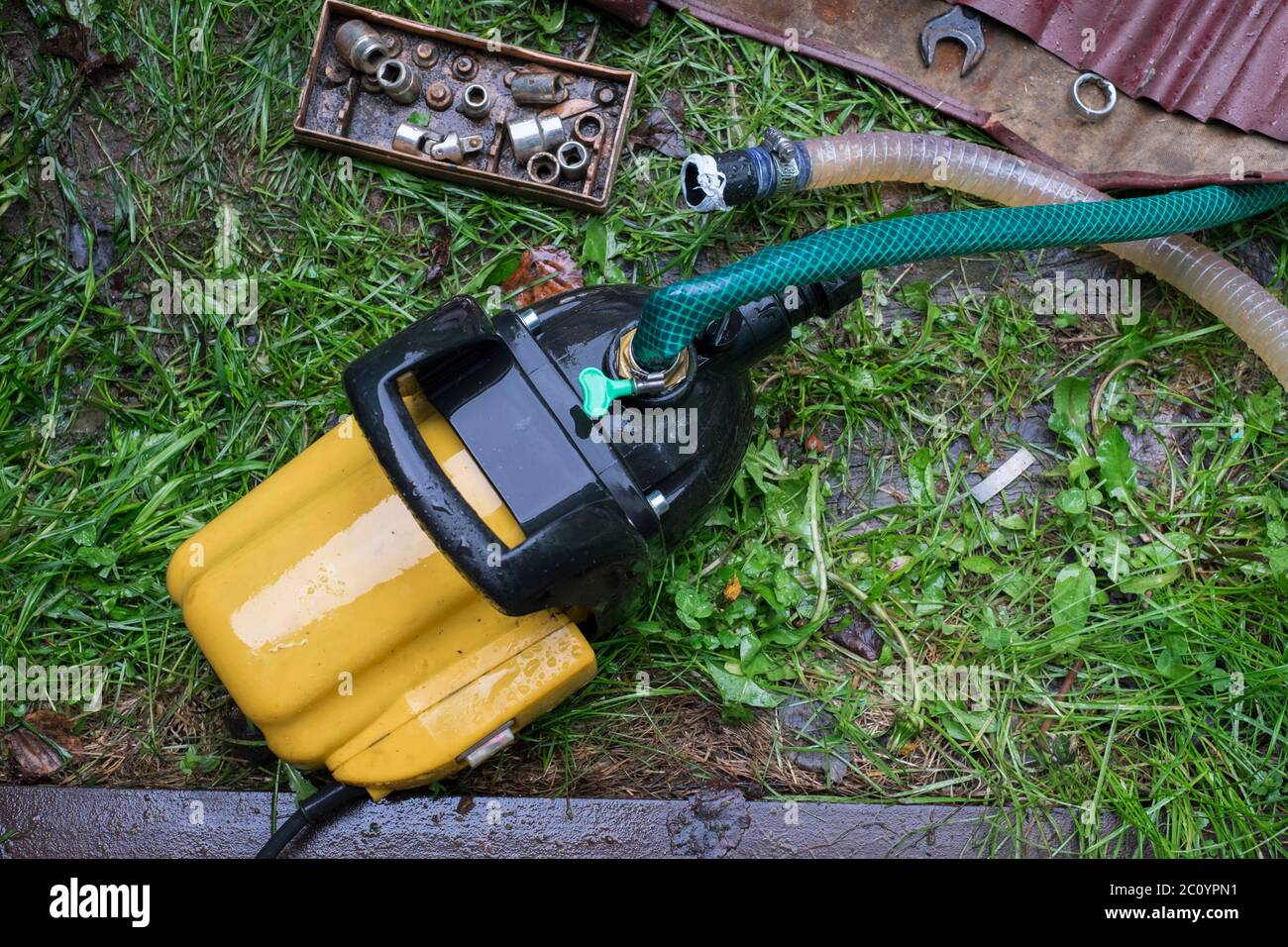 Réparation d'une pompe à eau de jardin, outils éparpillés sur le sol Banque D'Images