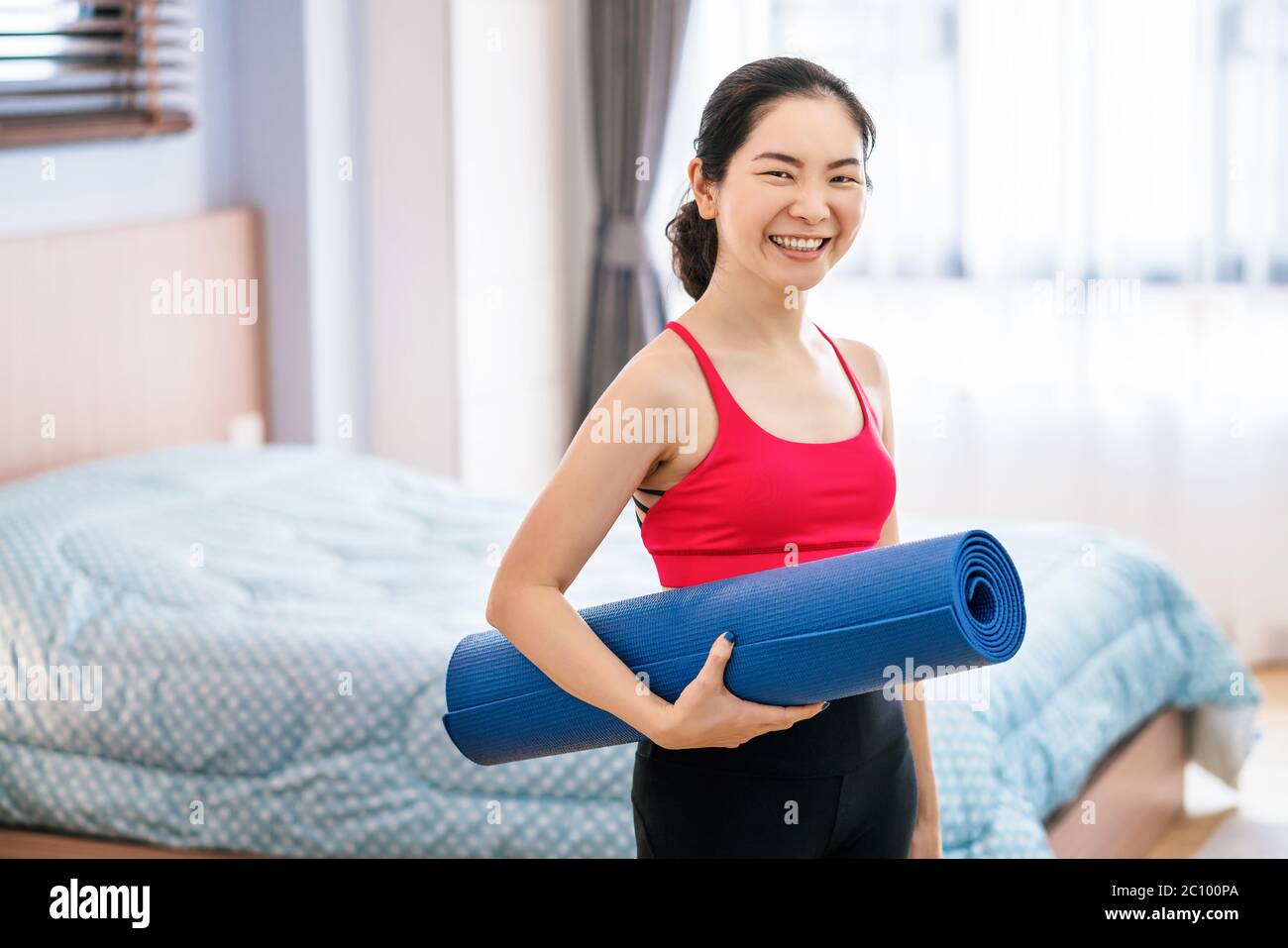 Portrait d'une femme asiatique tenant le tapis de yoga avant de pratiquer le yoga depuis la maison quand Covid19 épidémie et verrouillage, entraînement à la maison, courrivirus pandemi Banque D'Images