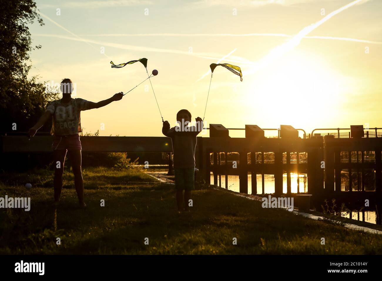 Mère et enfant balançant des points d'intérêt au coucher du soleil sur la rivière Medway en été, Kent Banque D'Images