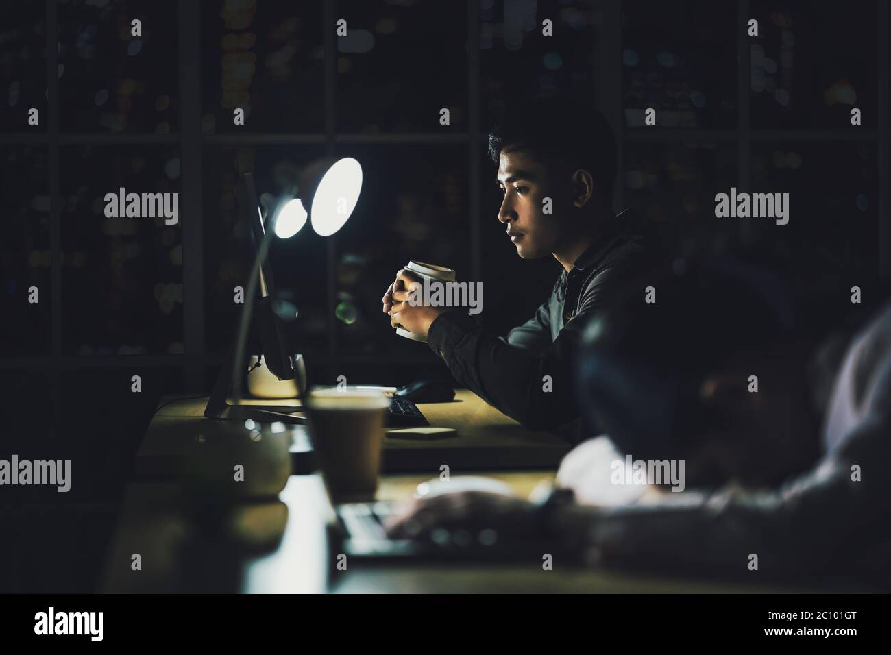 Homme d'affaires asiatique travaillant dur tard avec son ordinateur portable technologique au bureau, service à la clientèle et service de centre d'appels, travailleur dur et heures supplémentaires, elle c Banque D'Images