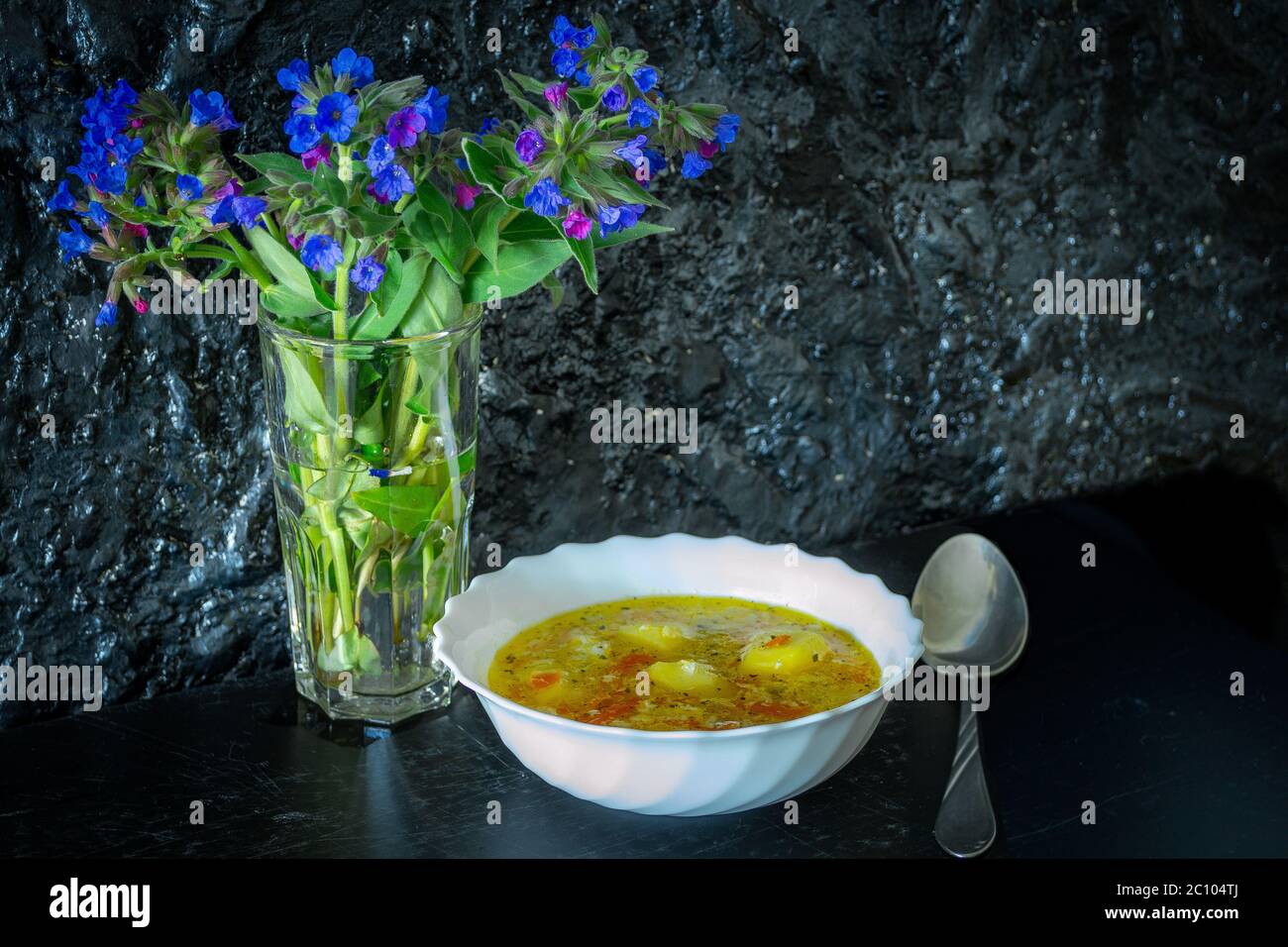 Soupe végétarienne légère sur fond noir avec fleurs sur la table Banque D'Images