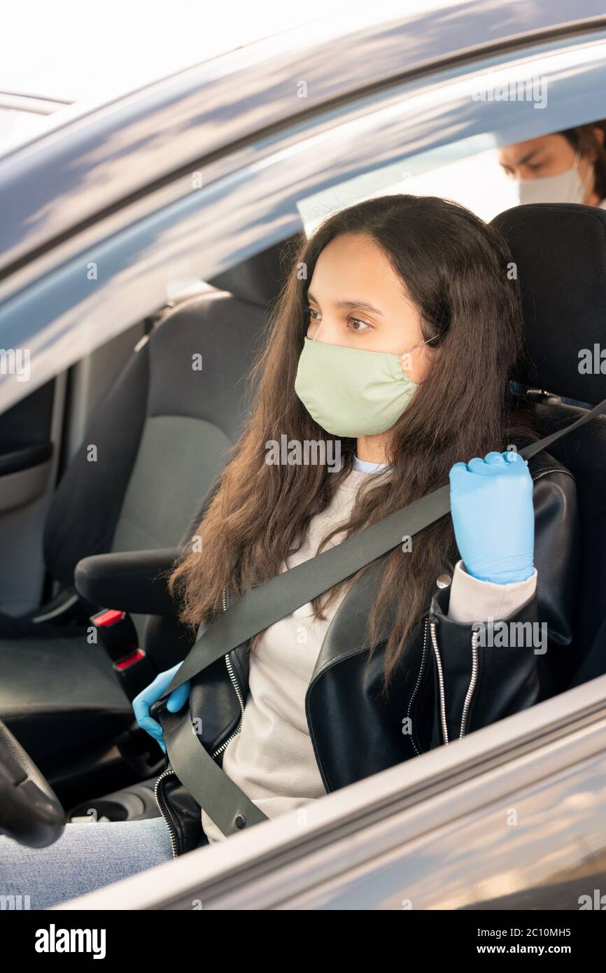 Une femme chauffeur de taxi portant un masque en tissu et des gants en  latex portant la ceinture de sécurité avant de prendre un taxi pendant une  pandémie de coronavirus Photo Stock -