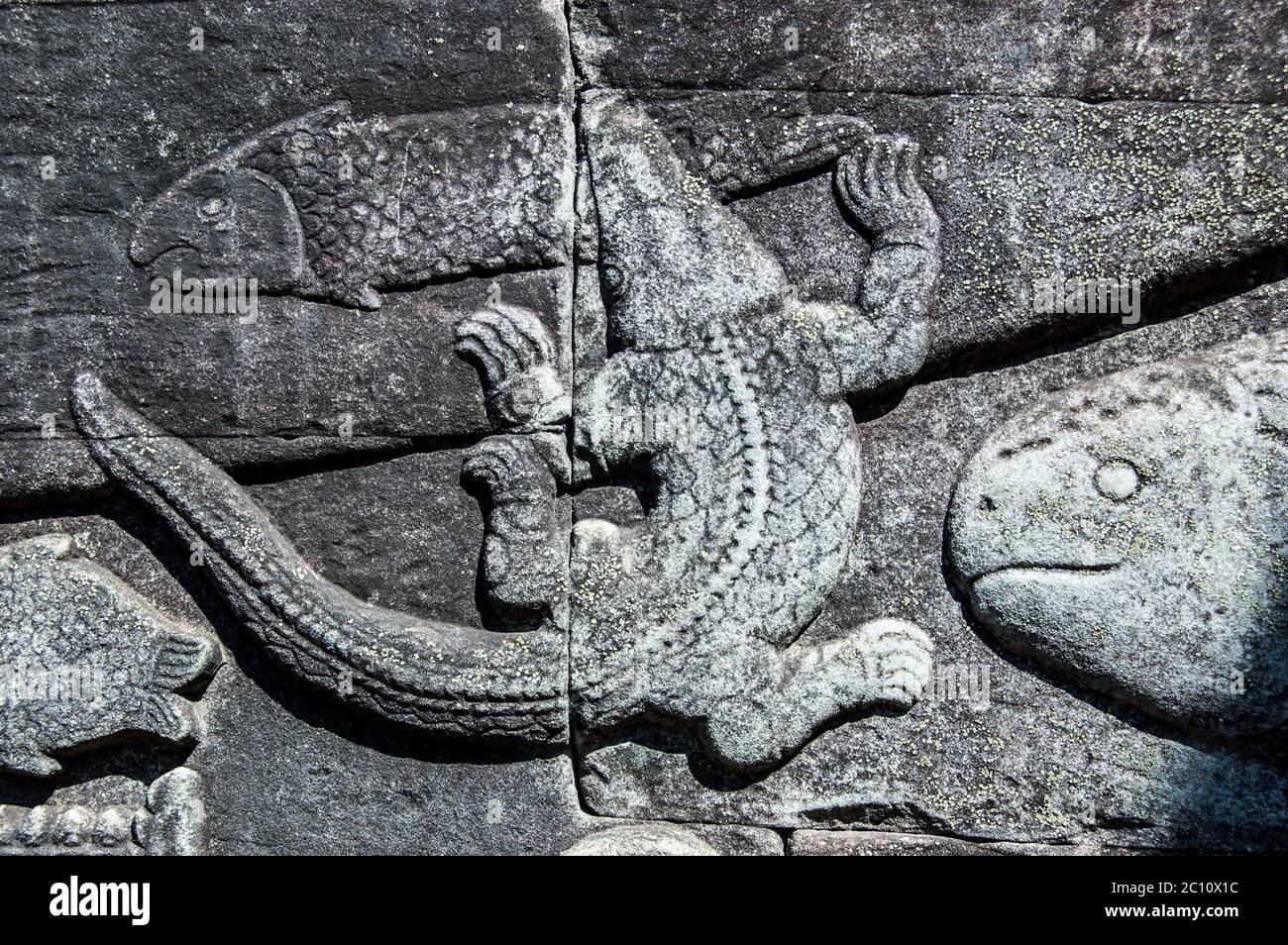 Ancienne sculpture de secours khmer montrant un crocodile attrapant un poisson dans le lac Tonle SAP. Temple Bayon, Angkor Thom, Siem Reap, Cambodge. Banque D'Images