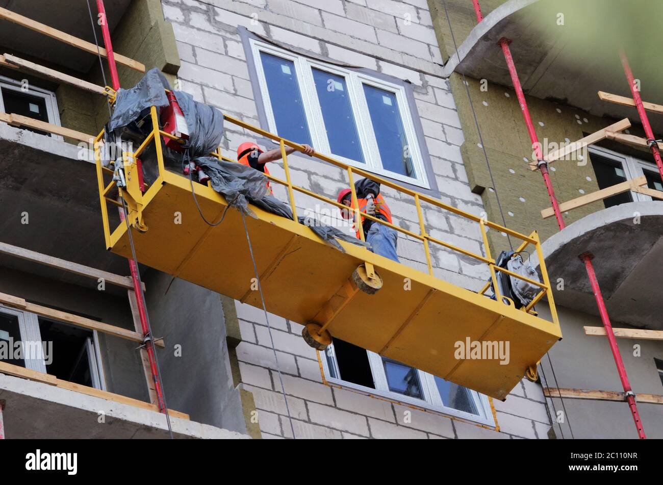 Berceau suspendu avec les travailleurs de la construction d'un nouvel immeuble de grande hauteur Banque D'Images