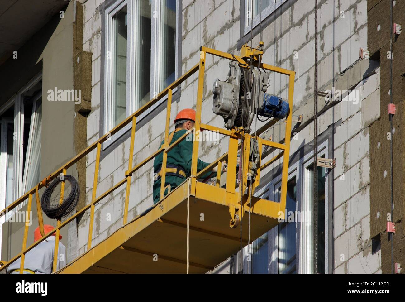 Berceau jaune suspendu la construction avec les travailleurs sur un nouvel immeuble de grande hauteur Banque D'Images