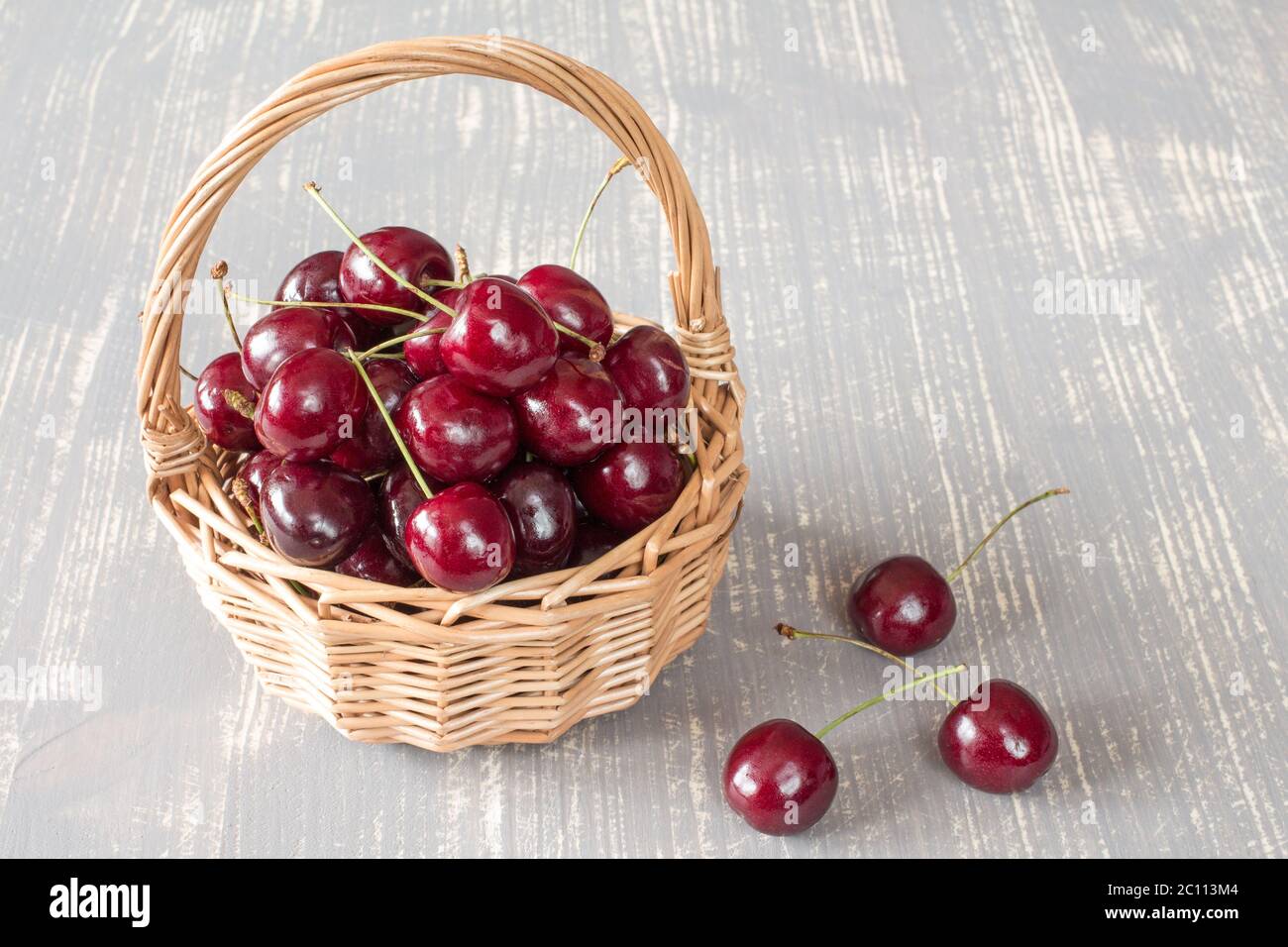 Panier en osier rempli de cerises fraîches Banque D'Images