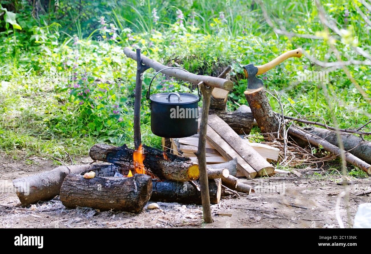 Pot touristique d'eau accrochée au-dessus d'un feu de bois dans le camping Banque D'Images
