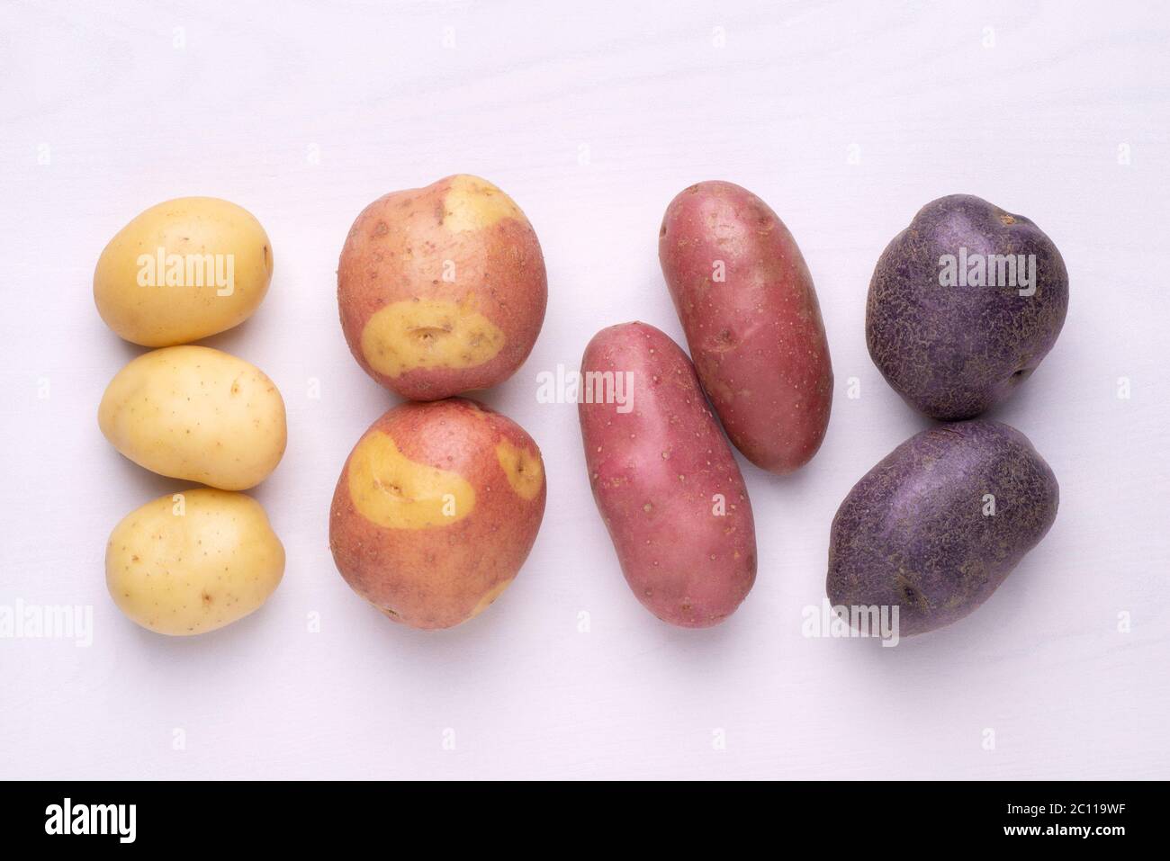 Différents types de pommes de terre sur table rustique en bois blanc Banque D'Images