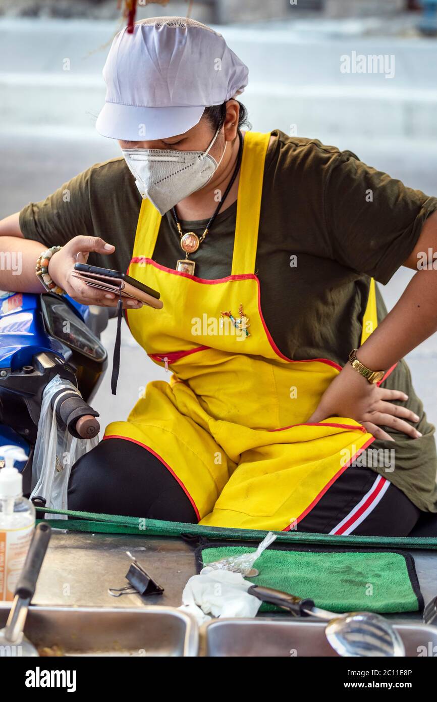 Vendeur de rue avec masque et téléphone mobile pendant la pandémie Covid, Bangkok, Thaïlande Banque D'Images
