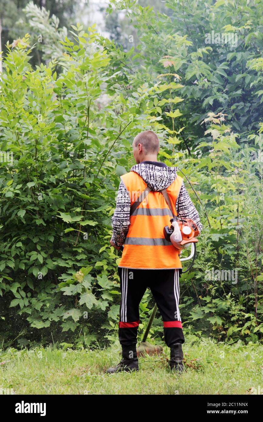 Un travailleur en uniforme tond la tondeuse à gazon. Banque D'Images