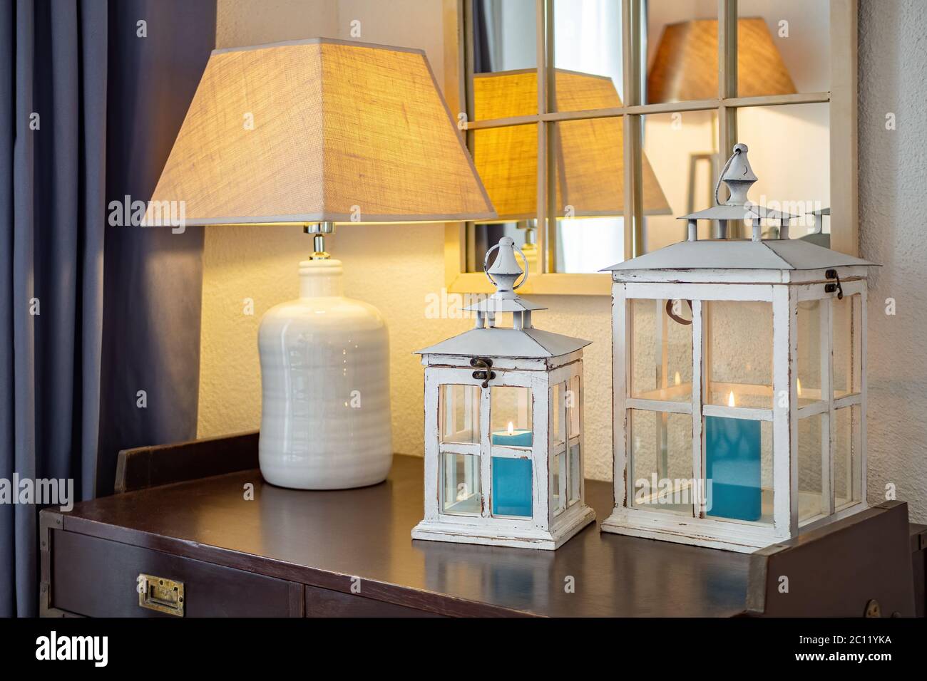 Lanternes en bois vintage, chandeliers avec bougies bleues à l'intérieur, placé sur une table sombre avec lampe dans une pièce confortable. Banque D'Images