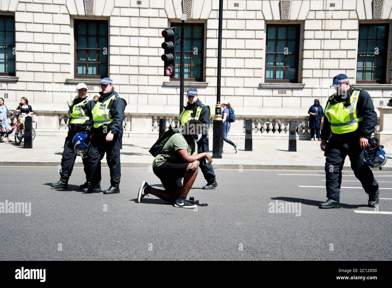 Place du Parlement. Un homme noir solitaire prend le genou tandis que les manifestants se rassemblent pour « protéger » la statue de Winston Churchill, accusé de racisme à cause de lui Banque D'Images