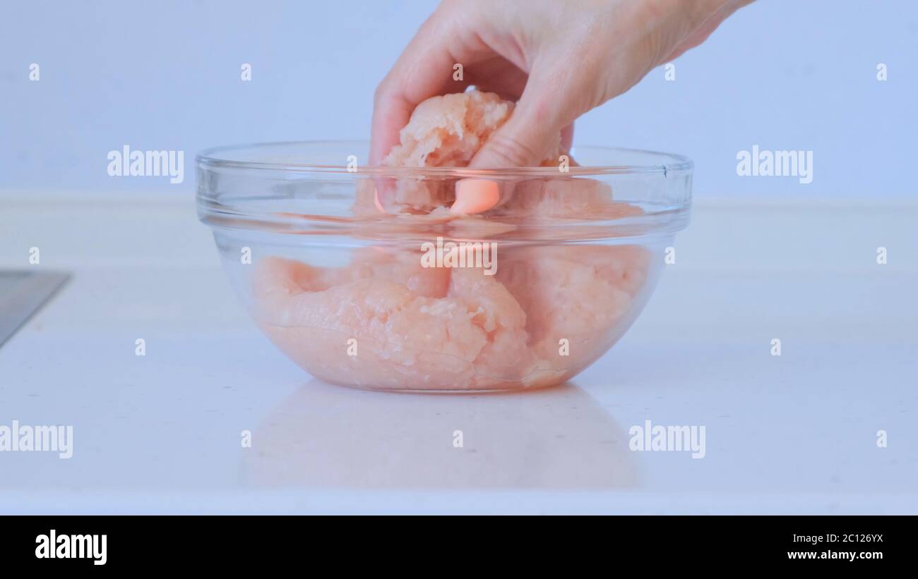 La fille prépare de la viande hachée. Une main féminine mélange le poulet haché et le porc. Plats à base de viande Banque D'Images