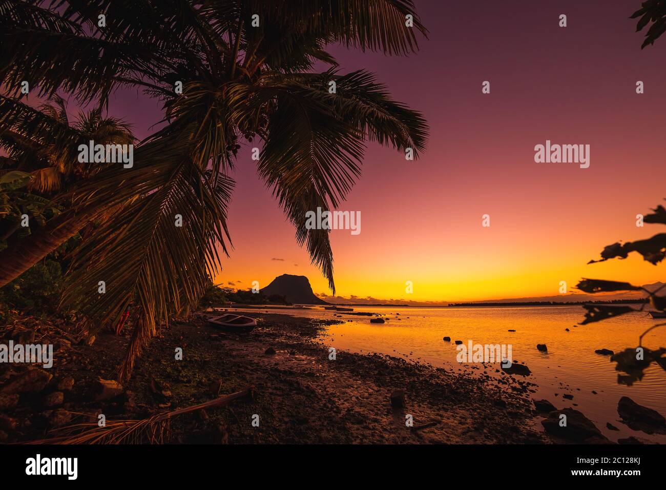 Bateau de pêche et noix de coco au coucher du soleil. Le Morn montagne en arrière-plan à l'île Maurice. Banque D'Images