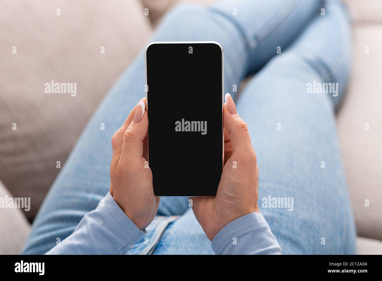 Gestion des flux de travail et affichage des formations en ligne. Une femme se trouve sur un canapé et tient un smartphone Banque D'Images