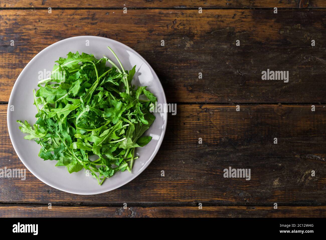 Salade roquette sur une assiette sur fond de bois. Banque D'Images
