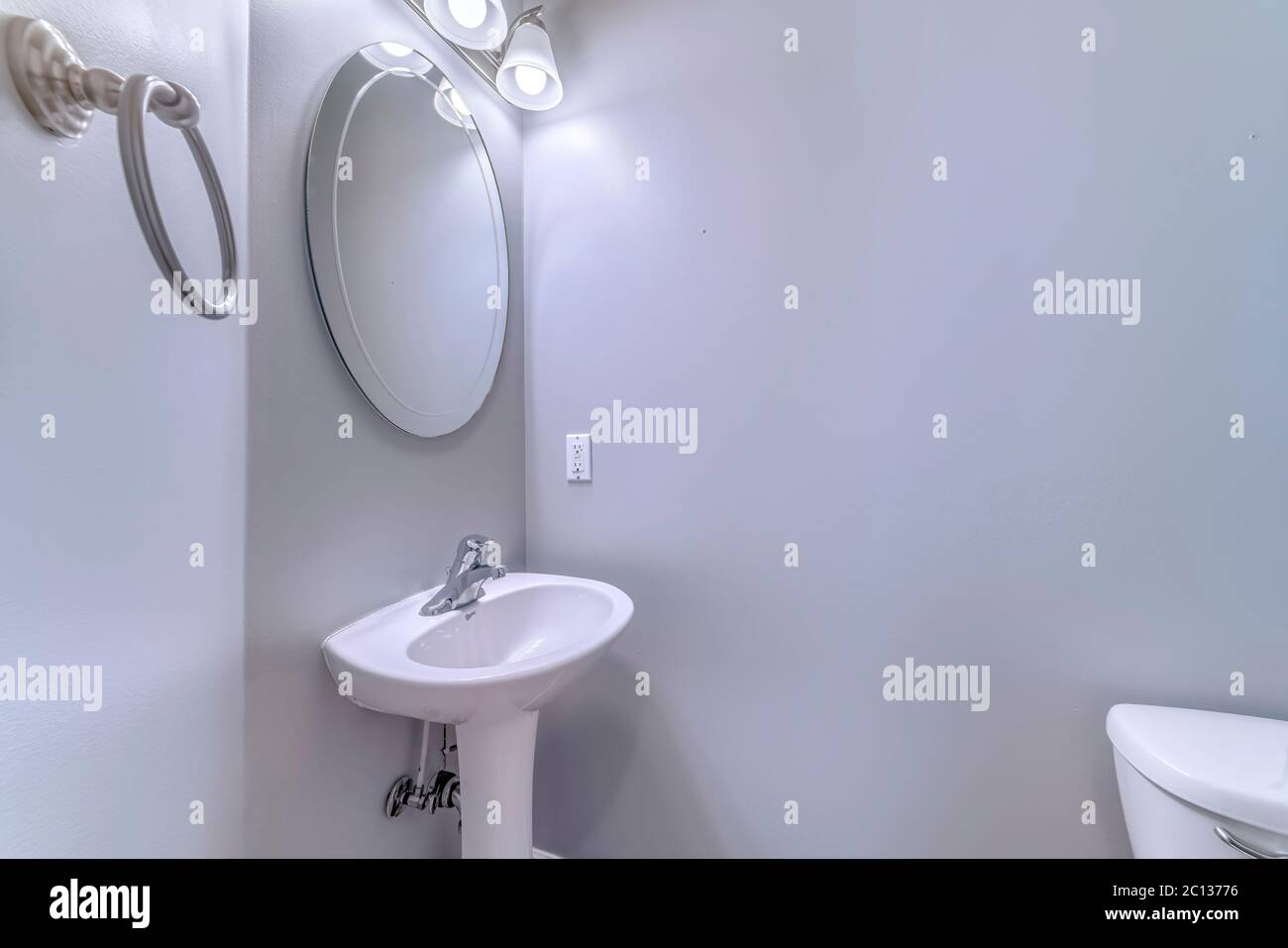 Intérieur de la salle de bains avec applique murale et miroir ovale sur lavabo sur pied Banque D'Images