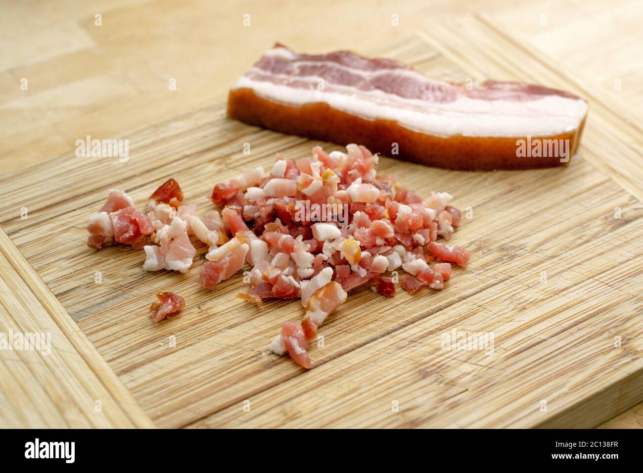 bacon tout entier et coupé en cubes sur une planche à découper en bois, mise au point sélectionnée, profondeur de champ étroite Banque D'Images