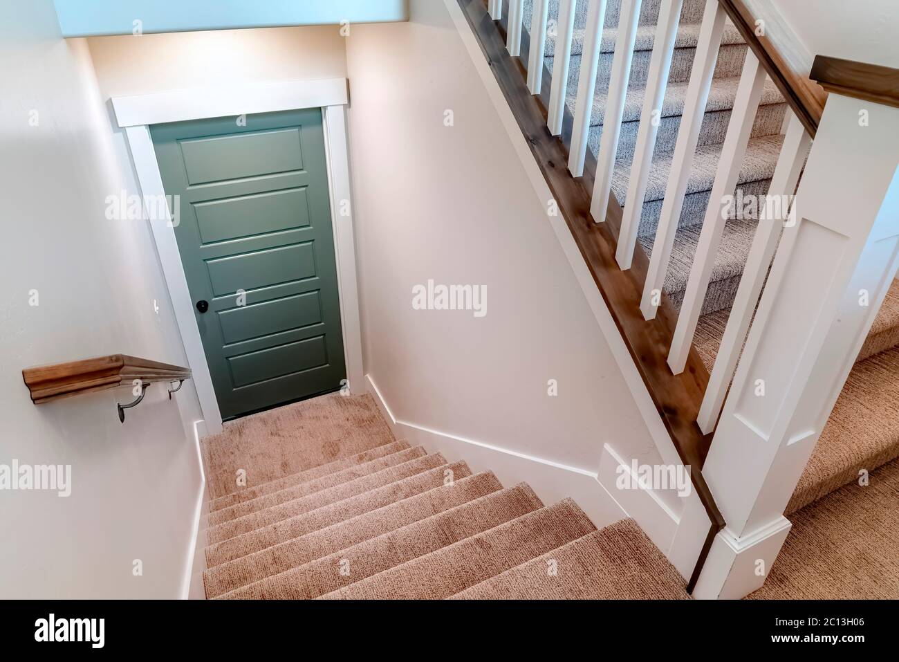 Escalier en U recouvert de moquette qui mène à la porte du sous-sol d'une maison Banque D'Images