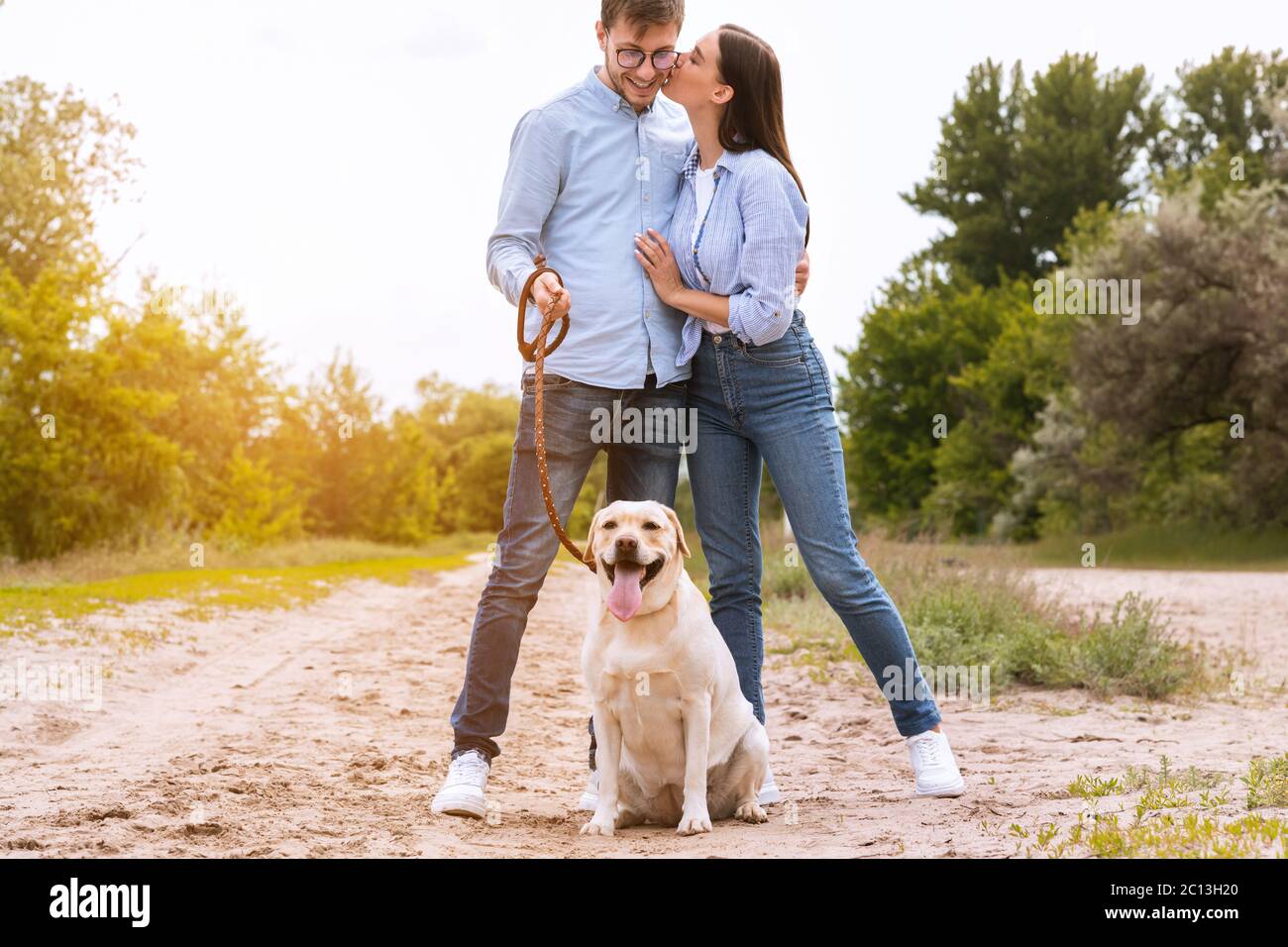 Portrait d'un jeune couple heureux qui marche avec un chien et qui embrasse Banque D'Images