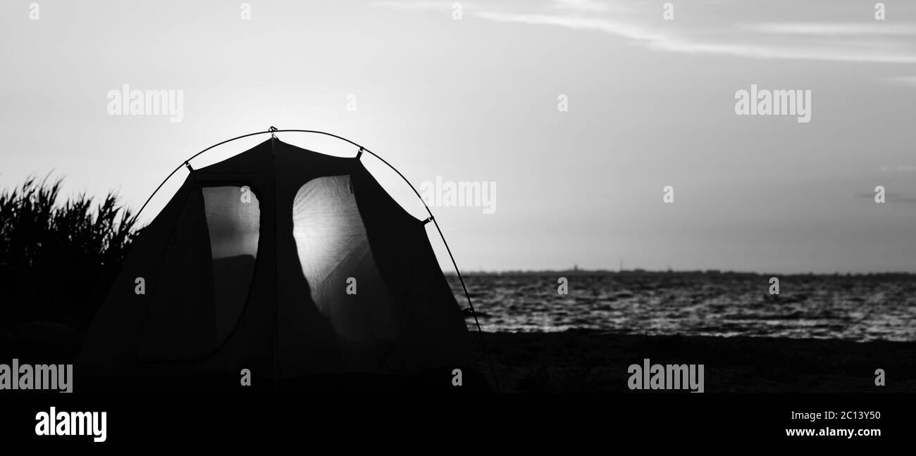 Vue panoramique sur la côte de mer et tente de camping avec une entrée sur la plage en soirée d'été. Paysage noir et blanc. Contraste élevé. Banque D'Images