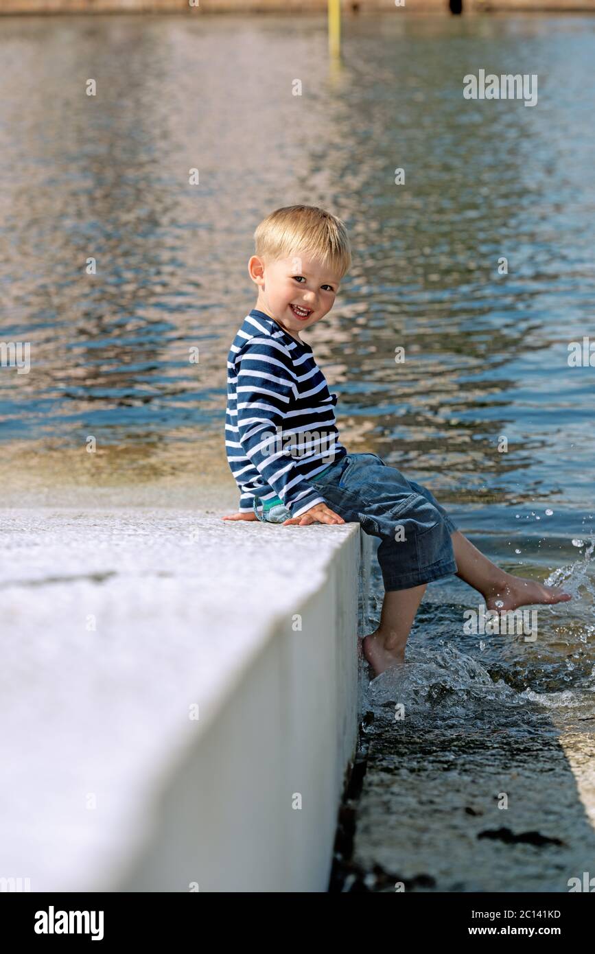 Petit garçon d'âge préscolaire posé sur la plage à l'extérieur Banque D'Images