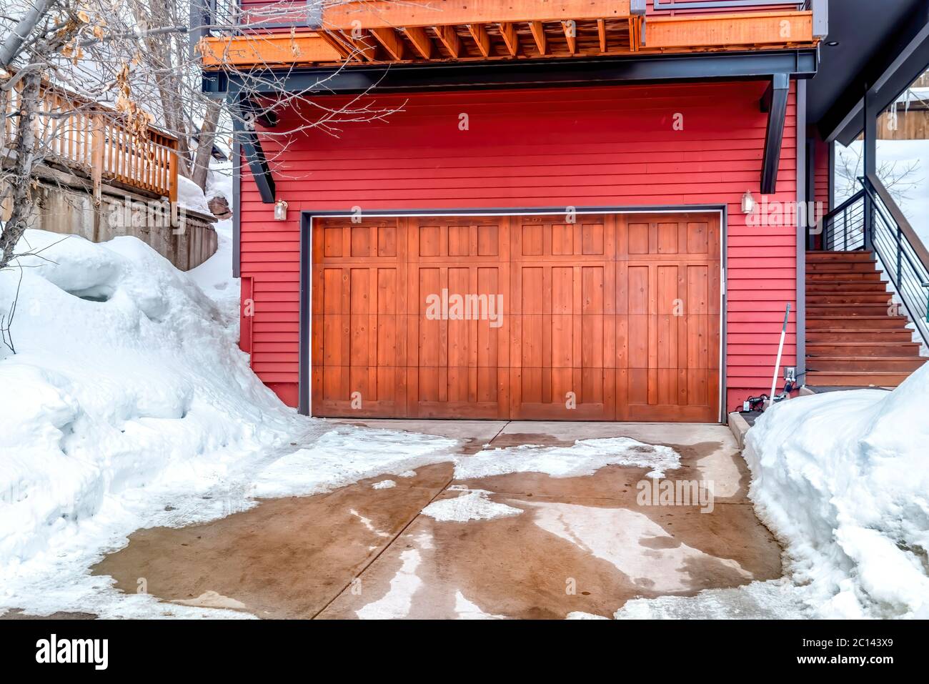 Porte de garage marron et mur rouge de la maison avec cour enneigée et  allée en hiver Photo Stock - Alamy