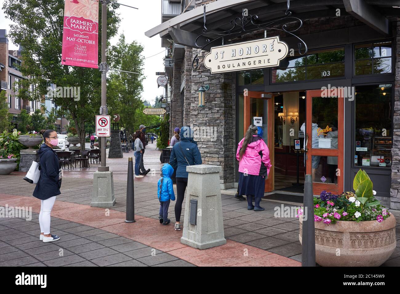 Les clients masqués font la queue et pratiquent la distanciation sociale à l'extérieur d'une boulangerie et d'un café du lac Oswego, Oregon, le 6/13/2020, pendant la pandémie de COVID-19. Banque D'Images