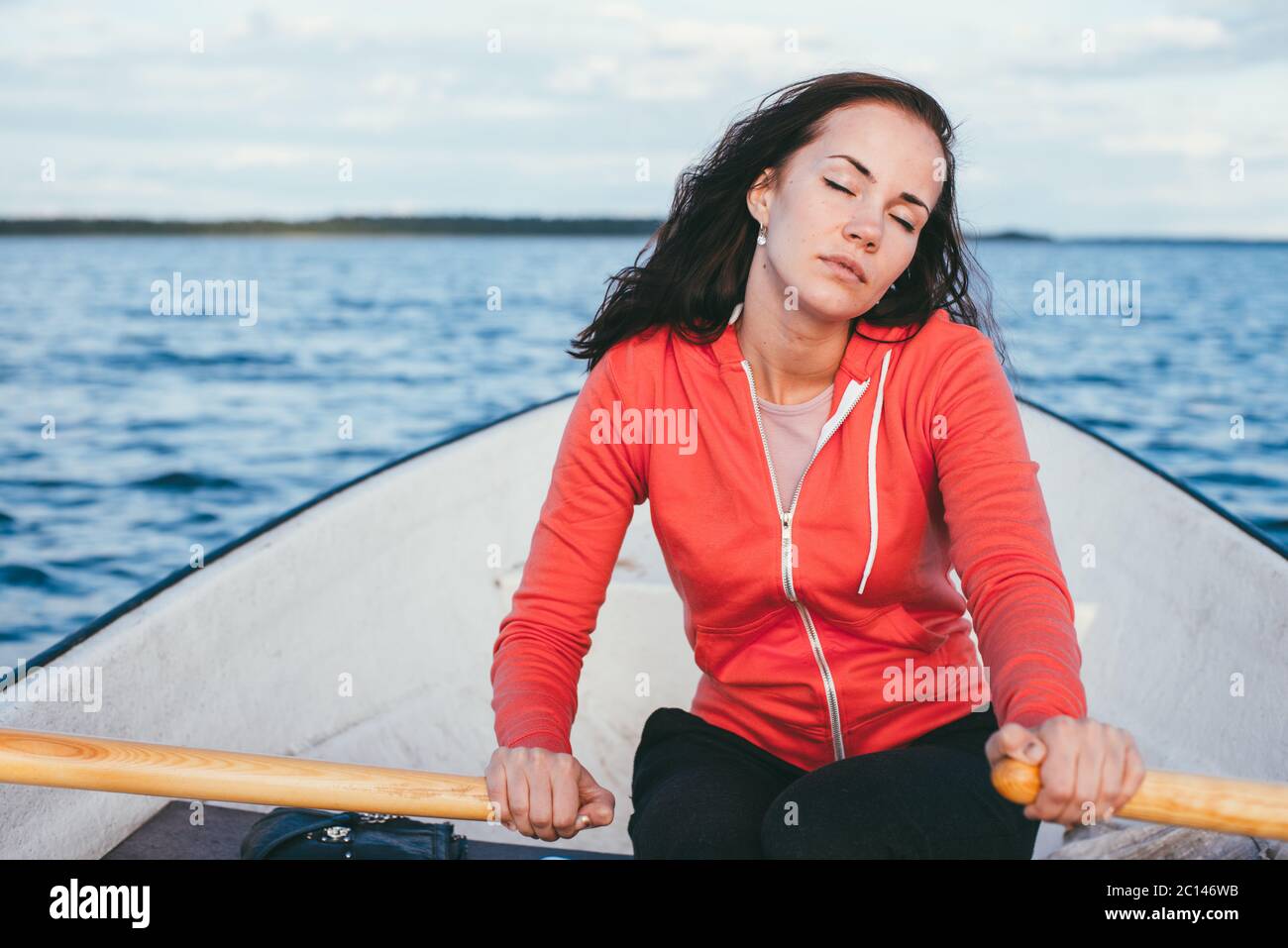 Amazing belle fille rousse nage sur un bateau en bois et de l'aviron à la rame dans le superbe lac de printemps. Vie sans maquillage Banque D'Images