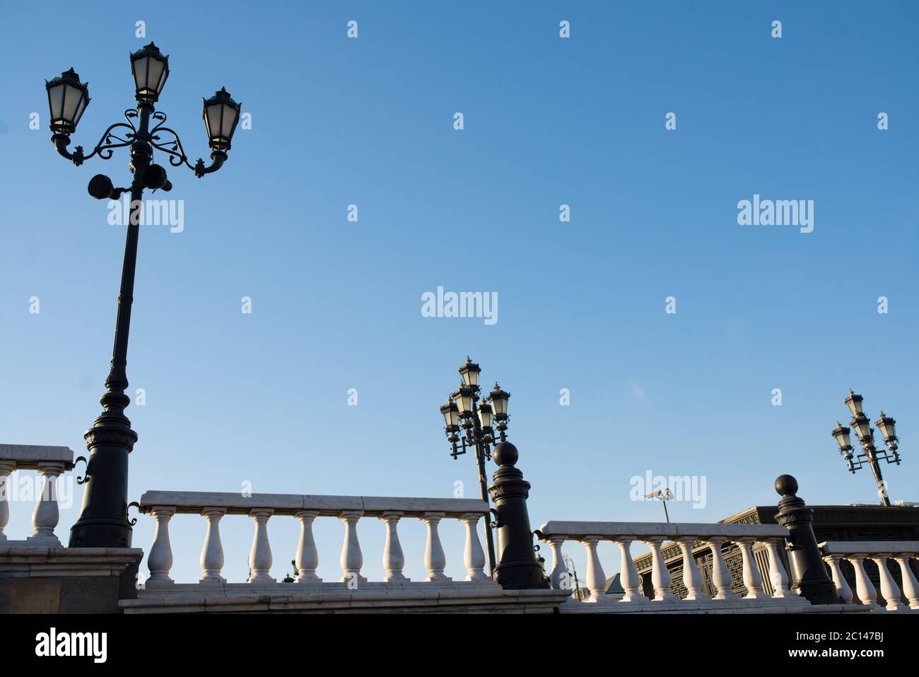 Lampadaires sur un quai avec rambarde à jour de printemps ensoleillé avec ciel bleu clair Banque D'Images