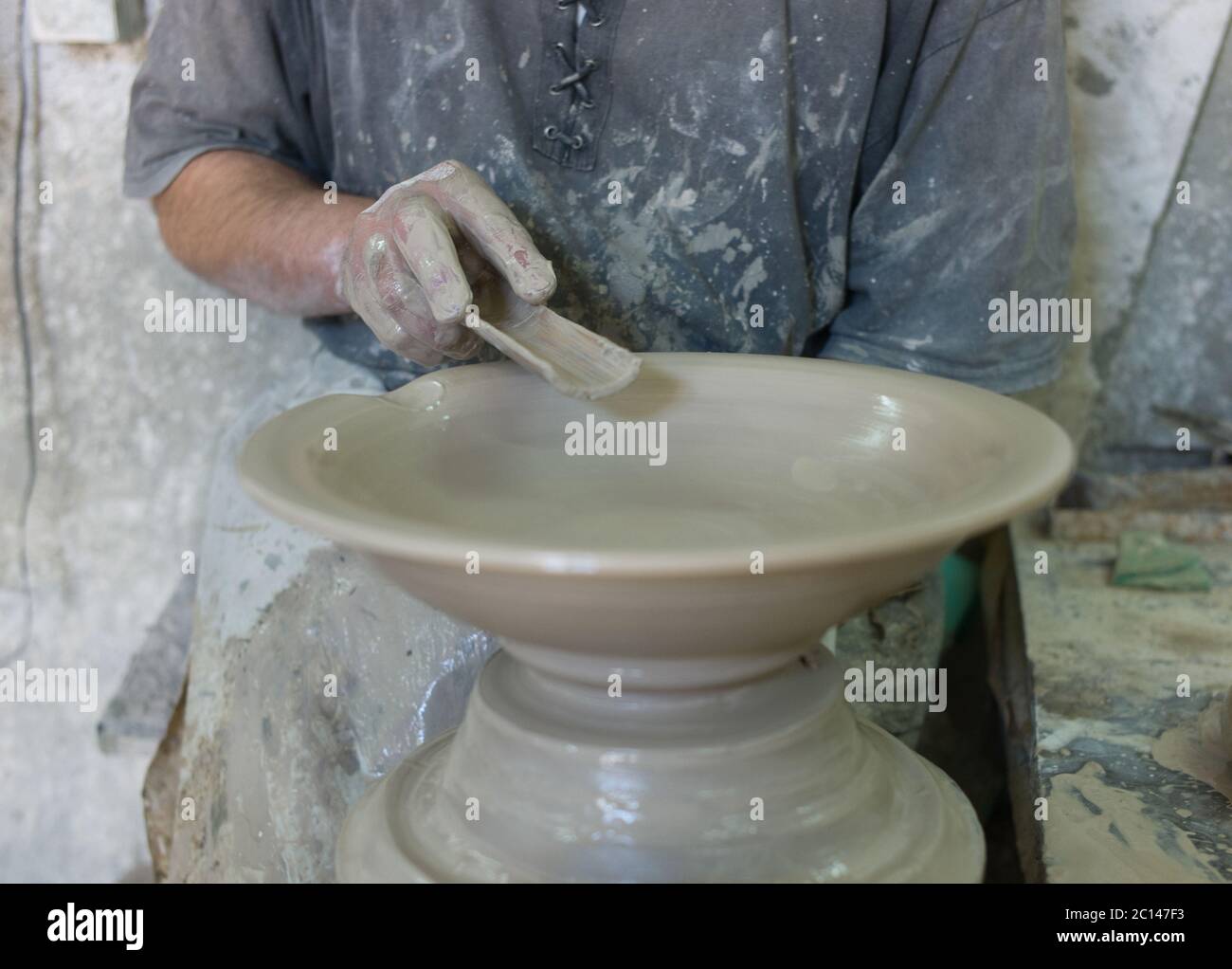 Un homme forme un bol pendant qu'il tourne sur une roue dans une usine de poterie à Fès, au Maroc. Banque D'Images