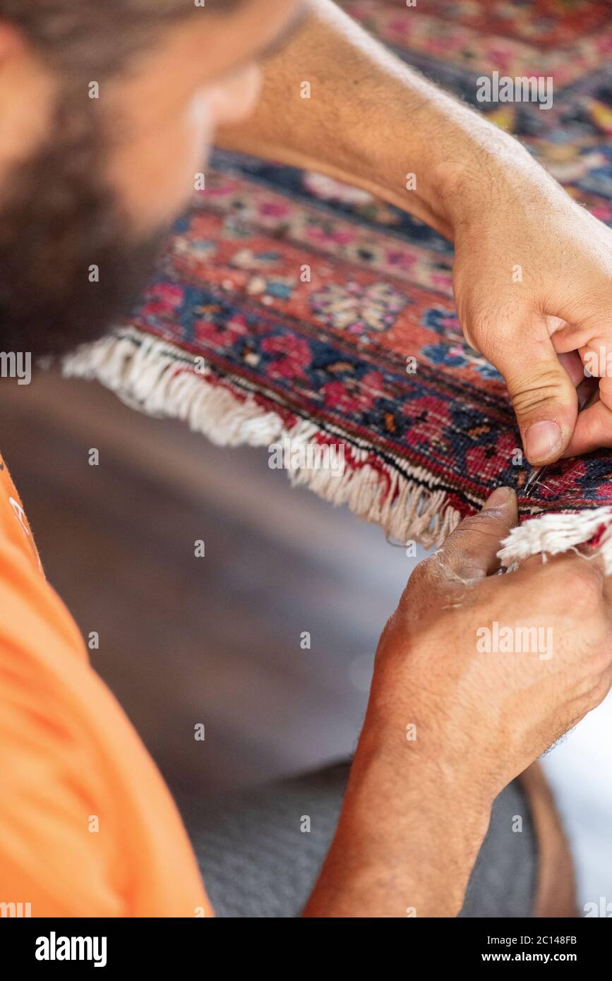 couture traditionnelle à la main fixant vieux vieux vieux tapis persan antique de près Banque D'Images