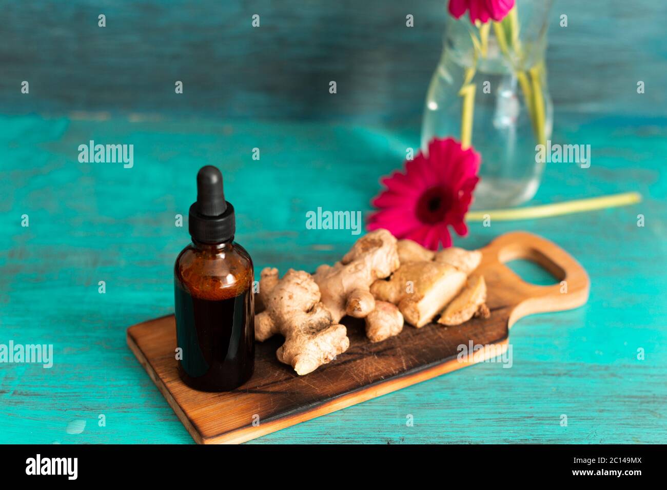 Boule de gouttes médicinales sur fond bleu avec gingembre et fleurs décoratives millésimes. Banque D'Images