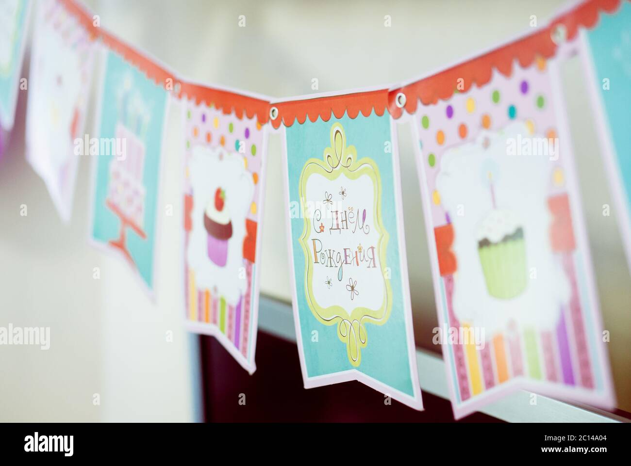 Vue rapprochée des drapeaux d'anniversaire colorés, guirlande avec des images de gâteau, bougies. Joyeux anniversaire en russe. Banque D'Images