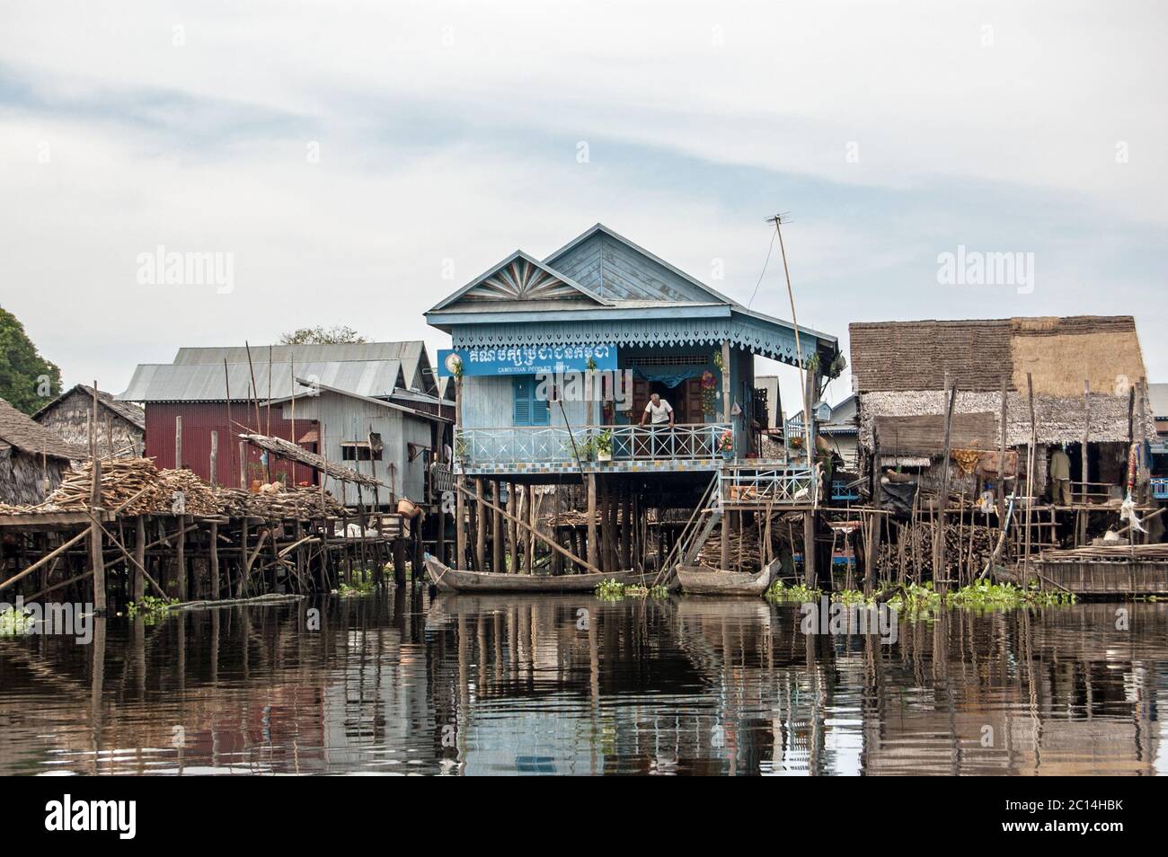 Kampong Phluk, Cambodge - 4 décembre 2011 : un homme se détendant sur la terrasse des bureaux du Parti populaire cambodgien, construit sur des pilotis dans le mal flottant Banque D'Images
