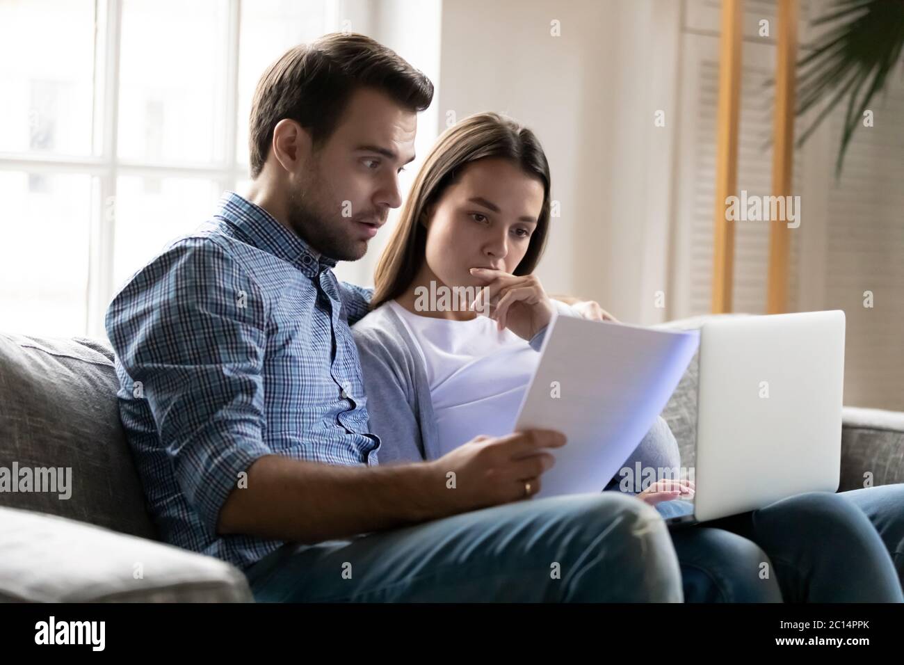 Choqué inquiet jeune couple lisant des documents, des problèmes financiers Banque D'Images