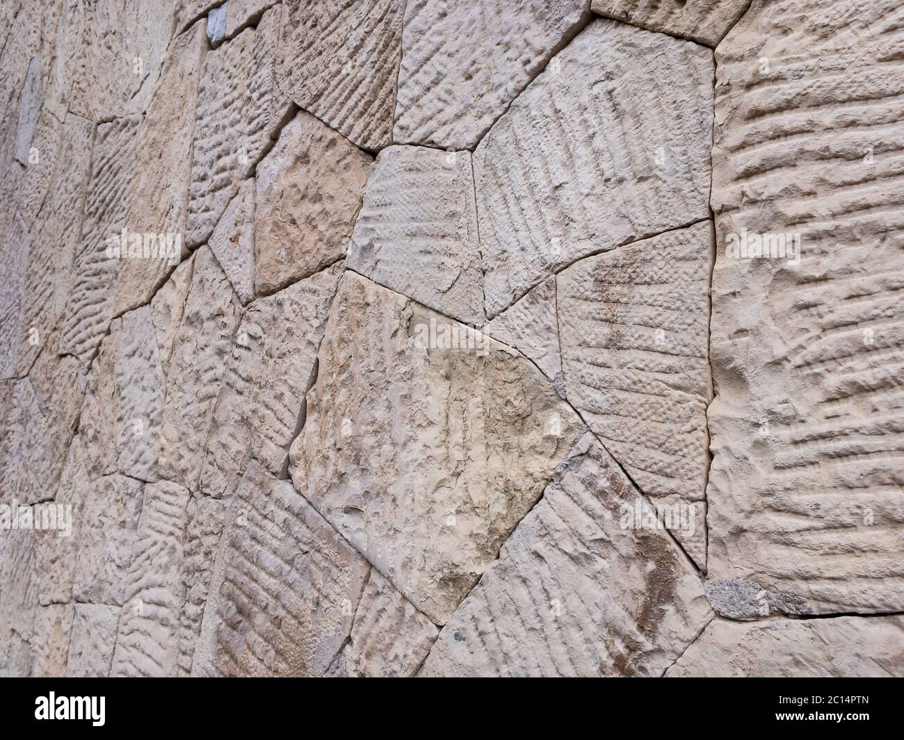 Vue en angle sur le mur brun de blocs de pierre de forme irrégulière et de surface inégale pour une utilisation en arrière-plan de gros plan. Banque D'Images