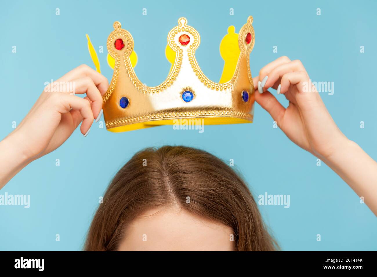 Gros plan de la femme mettant à la tête couronne dorée, concept de cérémonie de prix, statut privilégié, position supérieure, auto-motivation et grandes ambitions à Banque D'Images