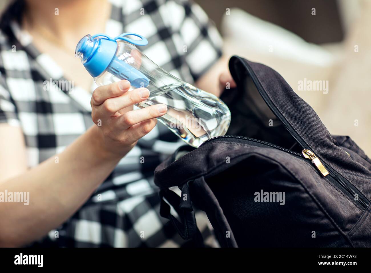 Une femme sort la bouteille du sac à dos. Femme prend le flacon réutilisable d'eau douce avec filtre au charbon de son sac à dos. Banque D'Images